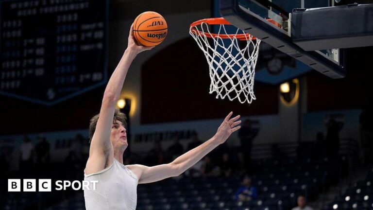 Olivier Rioux: 7ft 9in Florida Gators centre sets college basketball record Olivier Rioux warming up before a game. He has dark hair and is wearing a white sports vest. He is holding a ball in his raised right hand as he approaches the basket to score.
