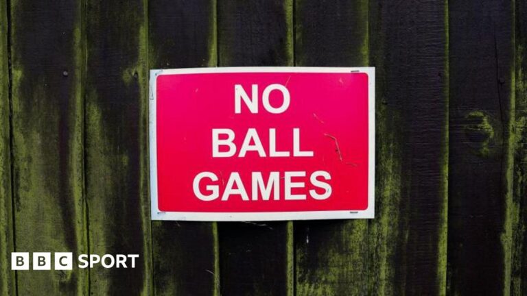 A red 'no ball games' sign on a fence