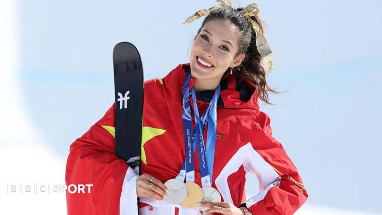 Eileen Gu poses while holding her three medals from the Milano Cortina 2026 Winter Olympics