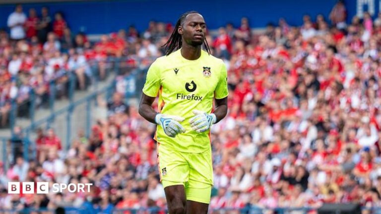 Arthur Okonkwo: Charlton Athletic sign Wrexham goalkeeper on loan Arthur Okonkow jogging on the pitch wearing fluorescent yellow Wrexham kit and white goalkeeper gloves